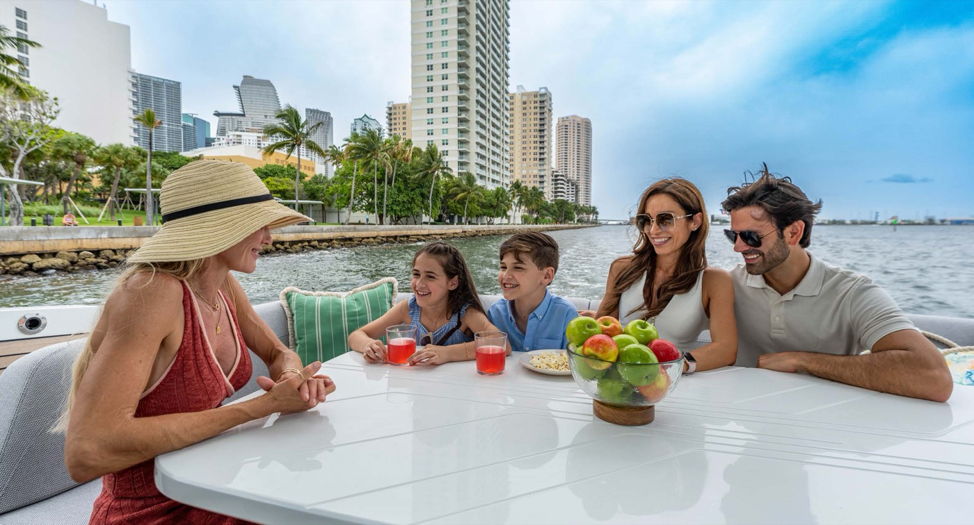 Family gathered around the flybridge dining table, city skyline behind