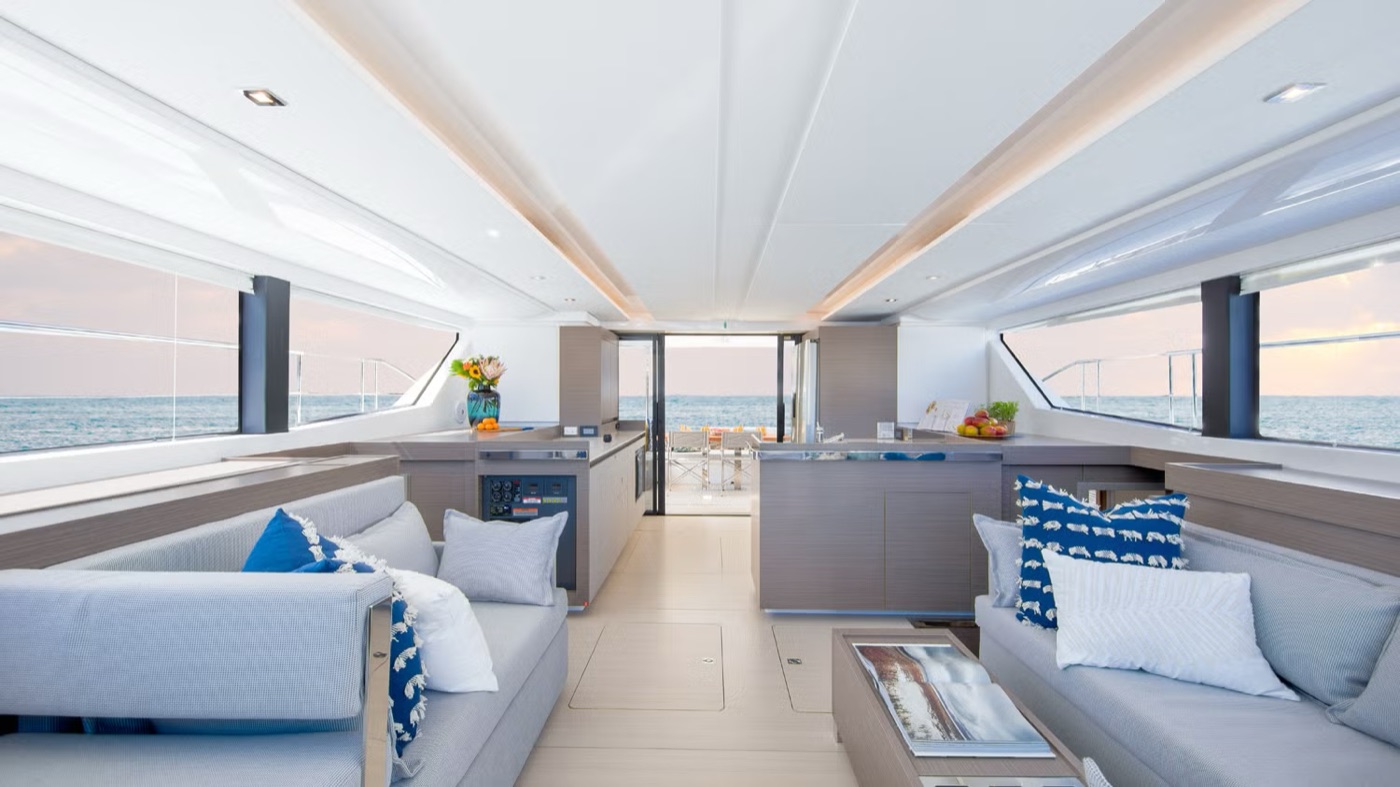 46PC salon and galley with crew at work, guests dining in the aft cockpit beyond
