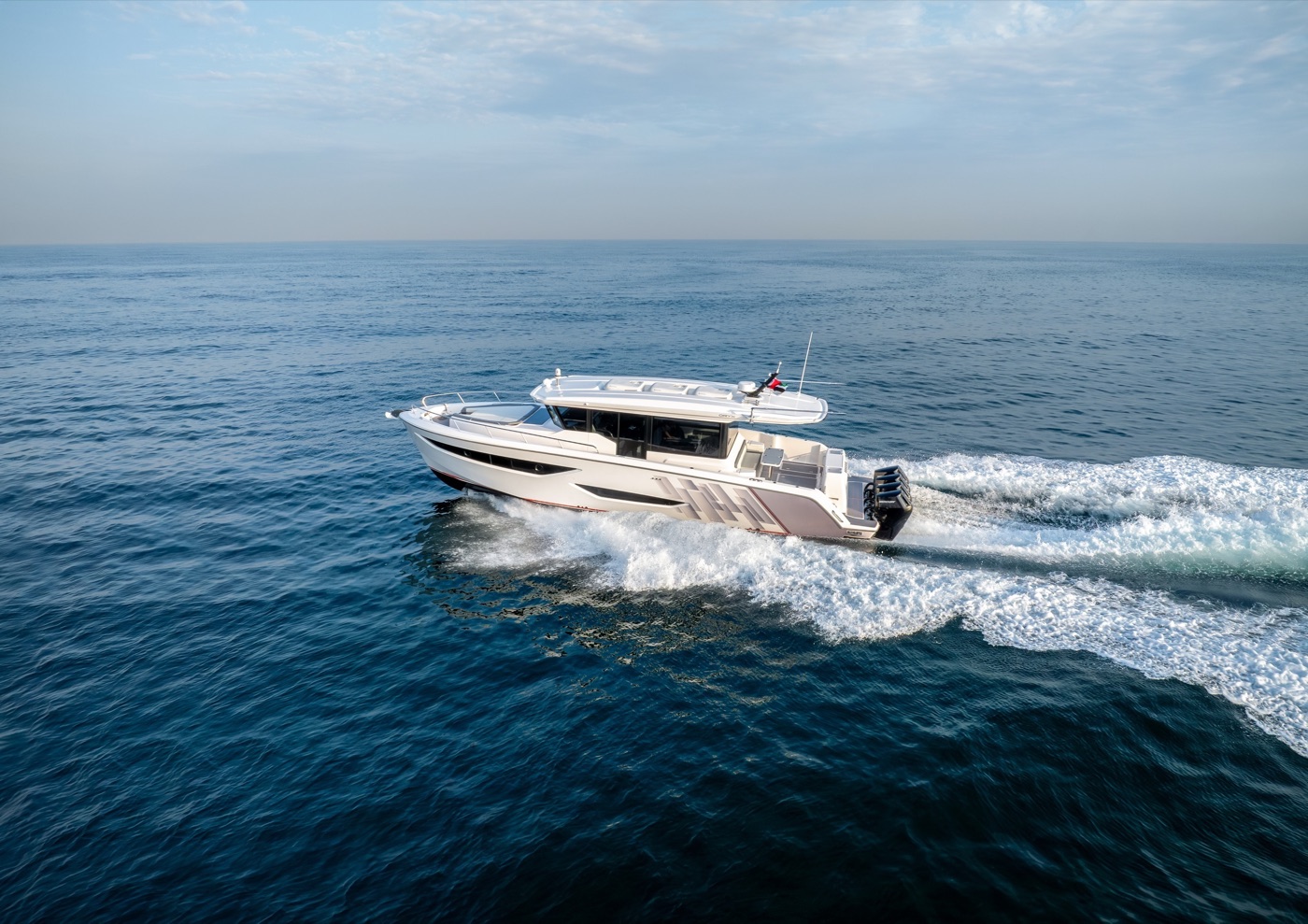 Oryx 47LX running toward a mountainous coastline at golden hour, quad outboards astern