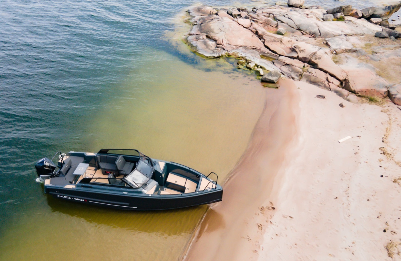Aerial view of the DSCVR 9 Open's open deck layout off a sandy shore