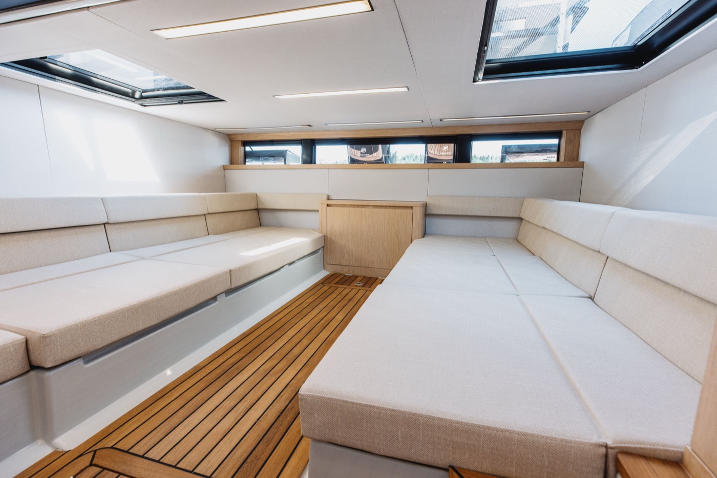 Lower saloon with white wraparound seating, teak sole and twin skylights